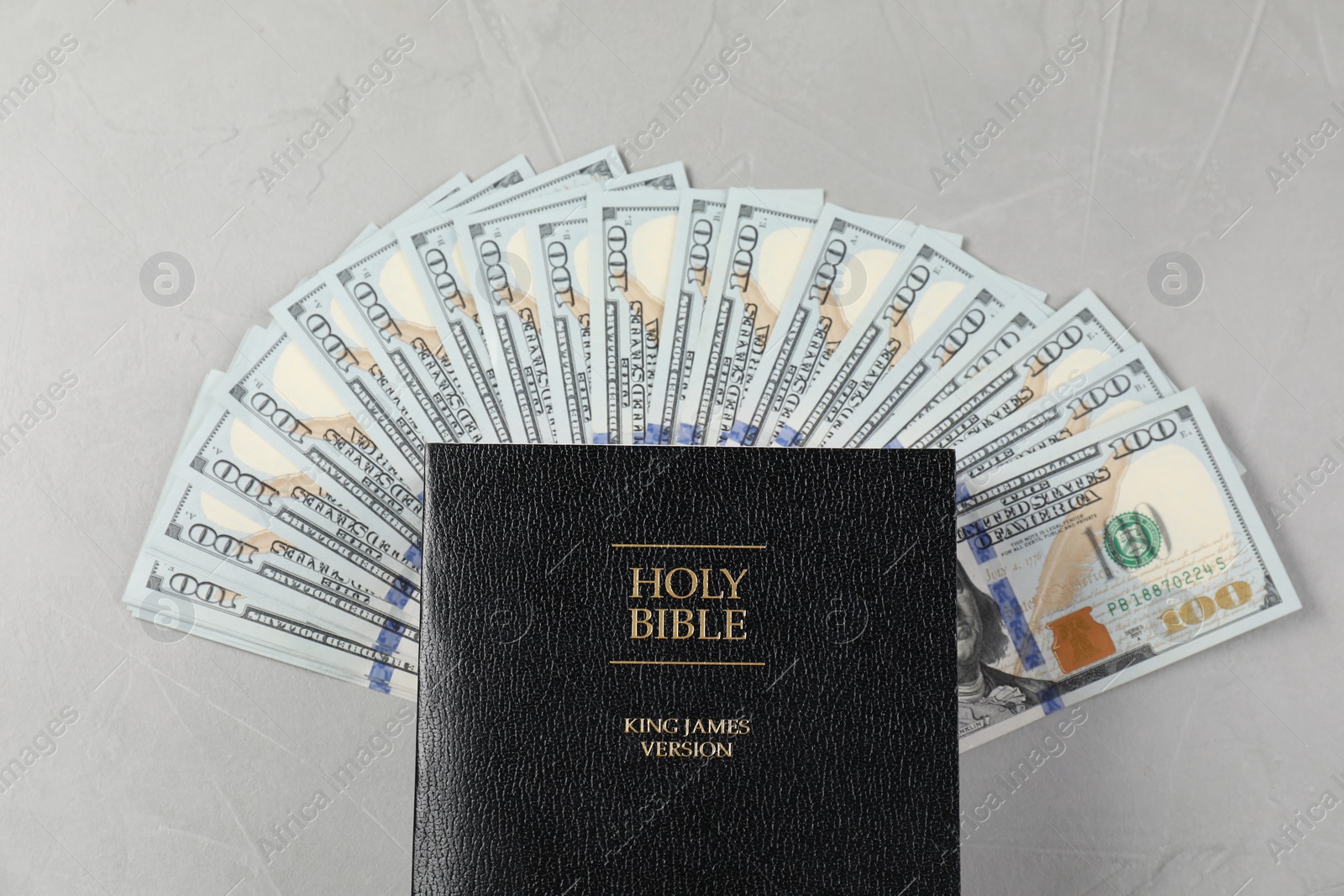 Photo of Holy Bible and money on grey table, top view