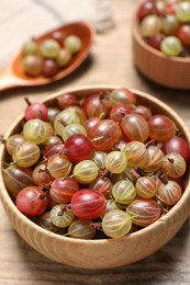 Bowl of fresh ripe gooseberries on wooden table, closeup