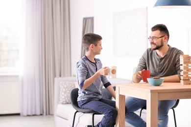 Photo of Little boy and his dad drinking tea together at home