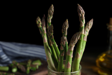 Photo of Fresh raw asparagus in glass on table, closeup view