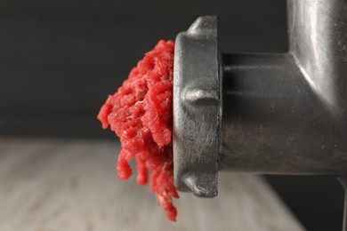 Photo of Mincing beef with metal meat grinder on blurred background, closeup