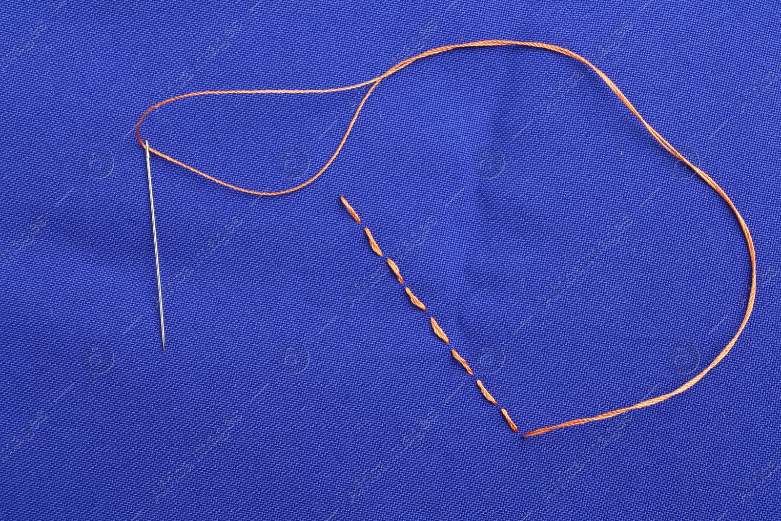 Photo of Sewing needle with thread and stitches on blue cloth, top view