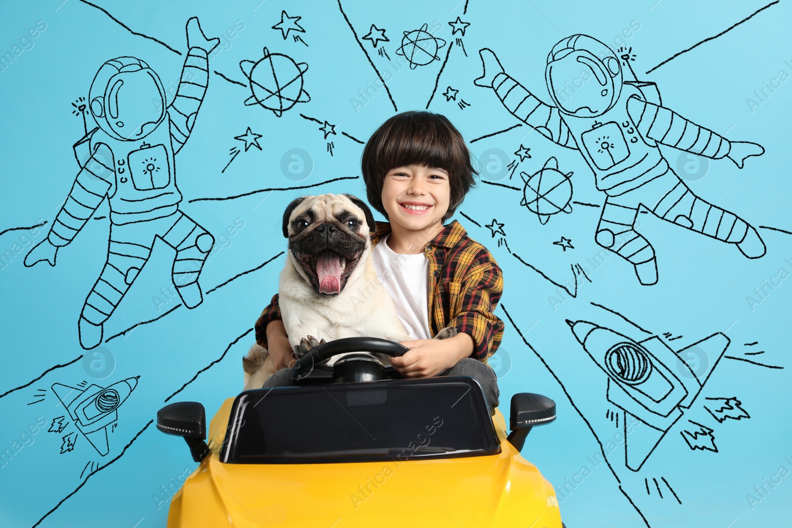 Image of Cute little boy with his dog in toy car and drawing of space on light blue background