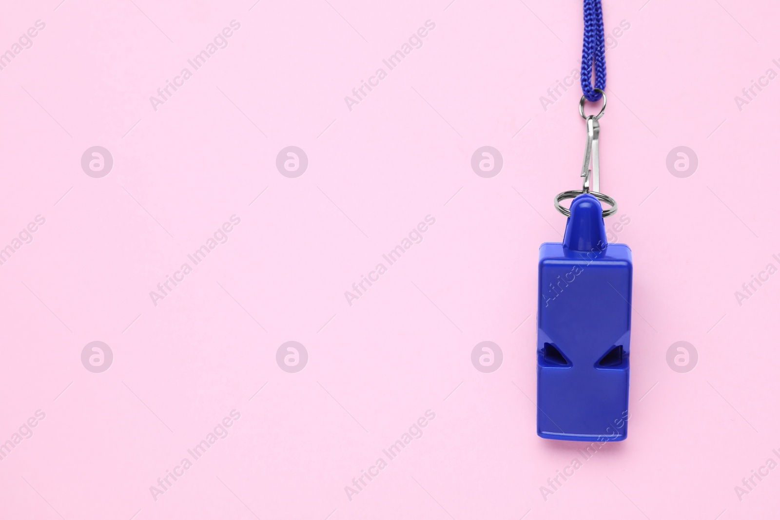 Photo of One blue whistle with cord on pink background, top view. Space for text