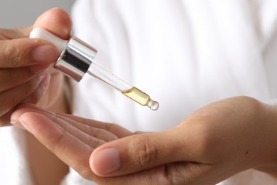 Photo of Woman applying cosmetic serum onto her hand, closeup