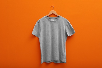 Hanger with blank t-shirt on color background. Mockup for design