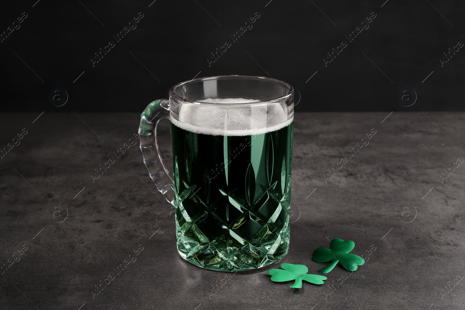 Photo of St. Patrick's day celebration. Green beer with decorative clover leaves on grey table