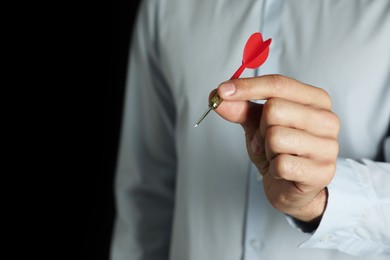 Photo of Man holding red dart on black background, closeup. Space for text