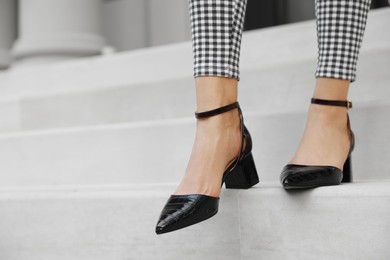 Photo of Woman in stylish black shoes walking down stairs, closeup