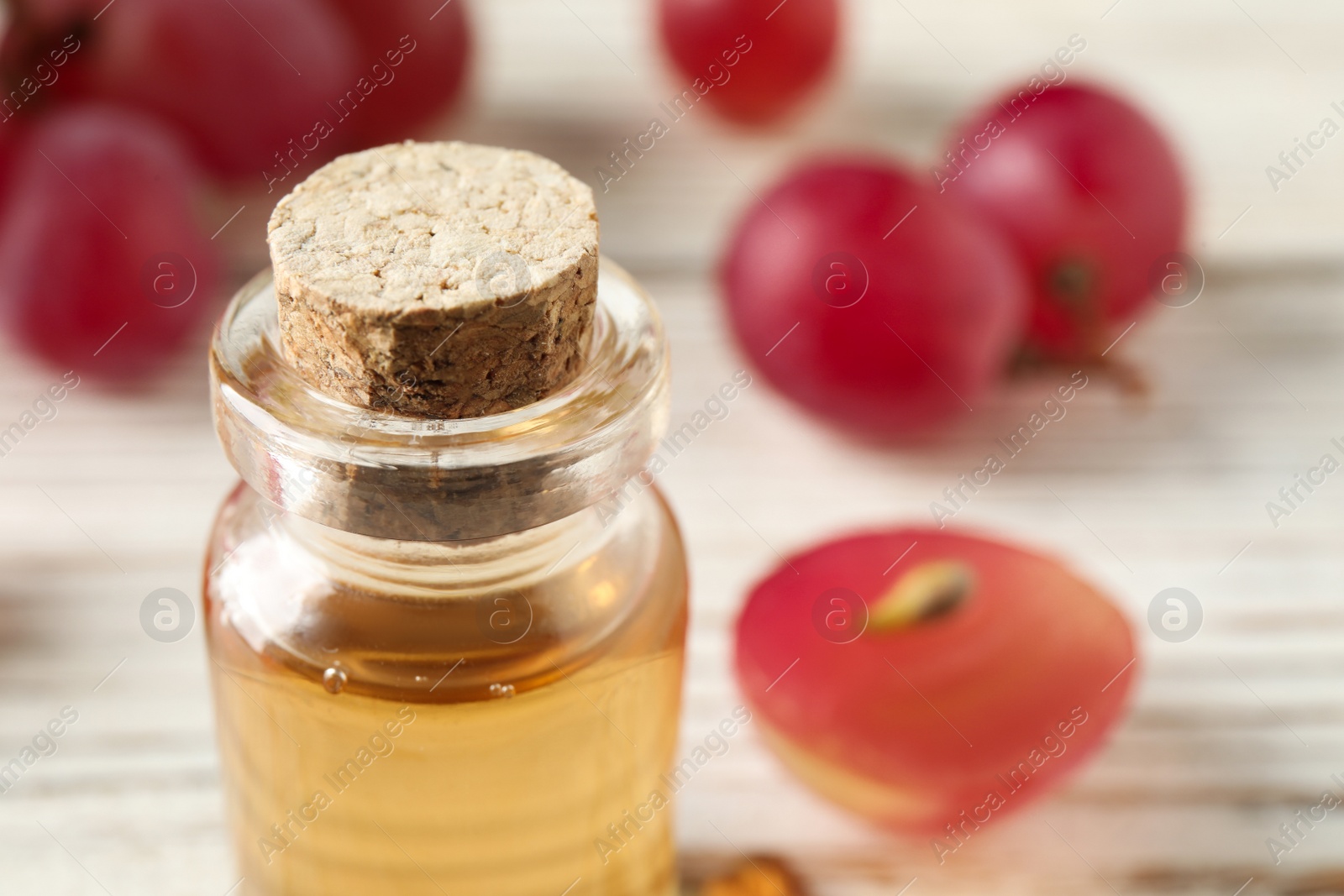 Photo of Bottle of natural grape seed oil on white table, closeup with space for text. Organic cosmetic