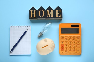 Photo of Flat lay composition with piggy bank and word Home made in shape of houses on light blue background