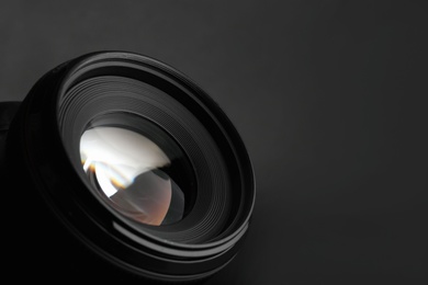 Photo of Modern camera lens on black background, closeup. Space for text