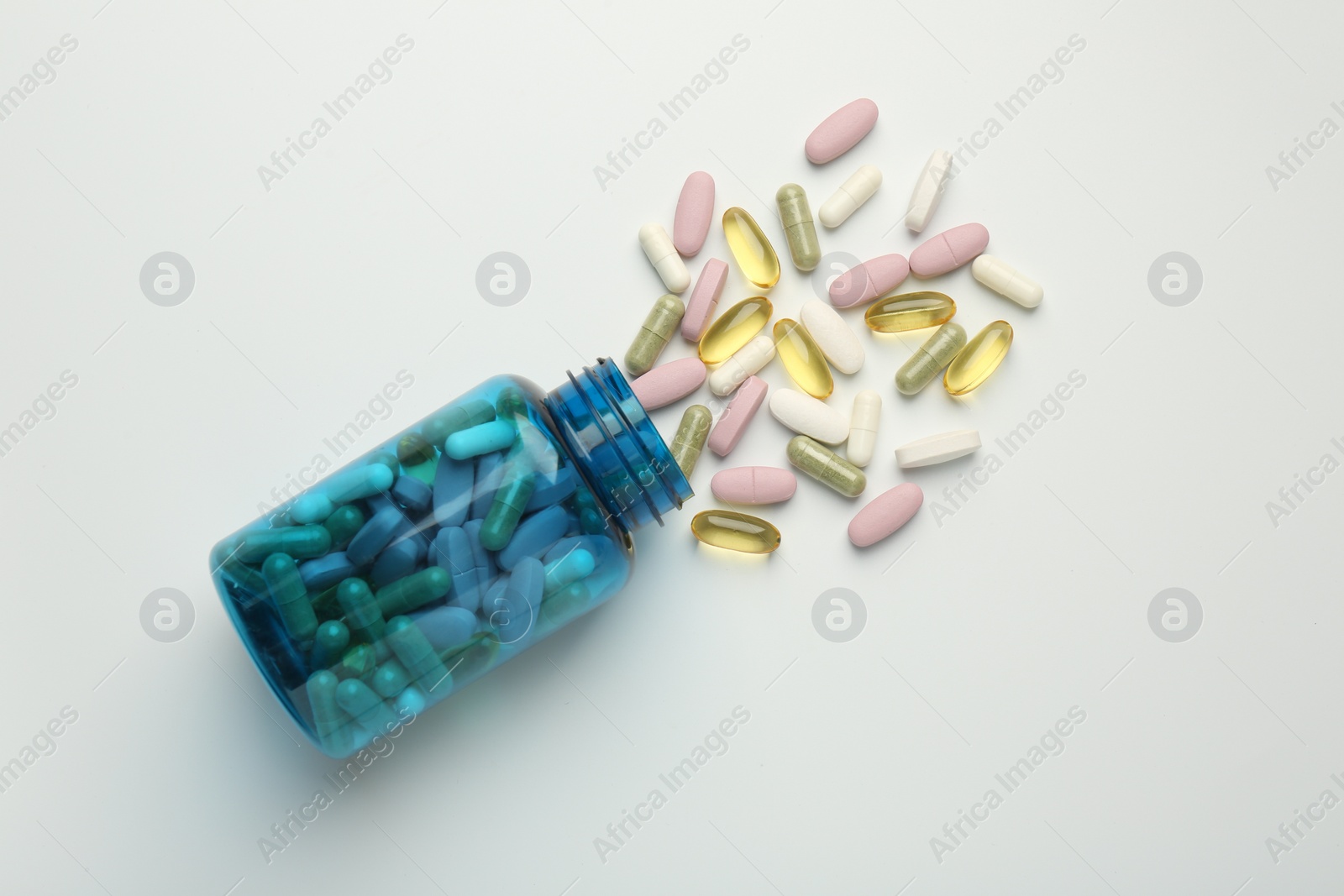 Photo of Vitamin pills and bottle on light background, top view