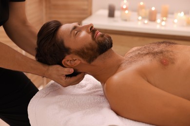 Photo of Man receiving professional neck massage in spa salon