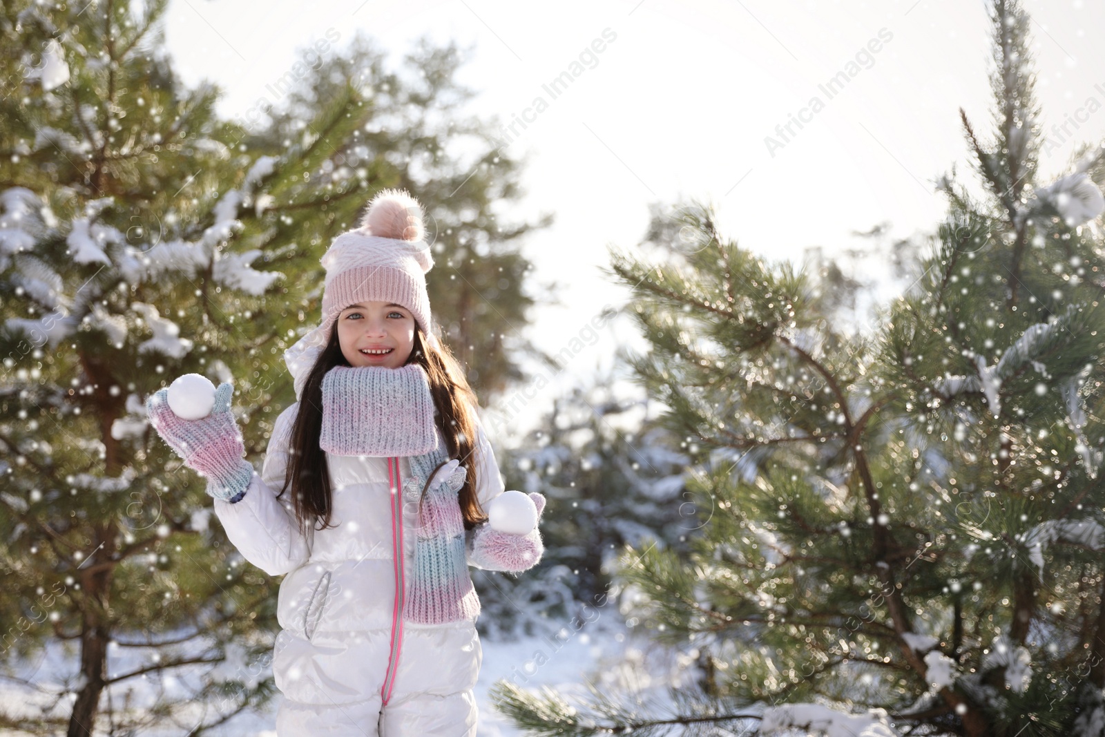 Photo of Cute little girl with snowballs outdoors on winter day. Christmas vacation