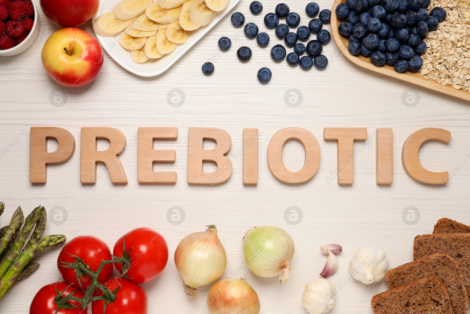 Photo of Word Prebiotic made of letters and foodstuff on white wooden table, flat lay