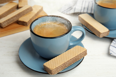 Delicious wafers and coffee for breakfast on white wooden table