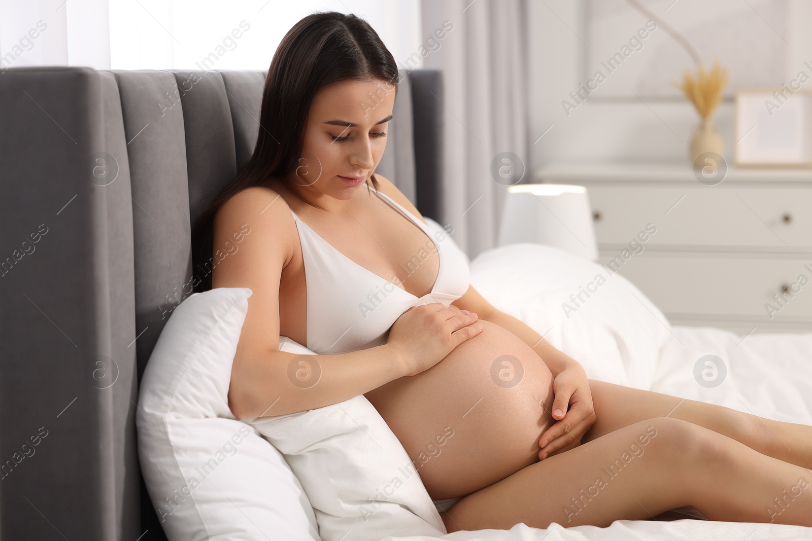 Photo of Beautiful pregnant woman in stylish comfortable underwear on bed at home