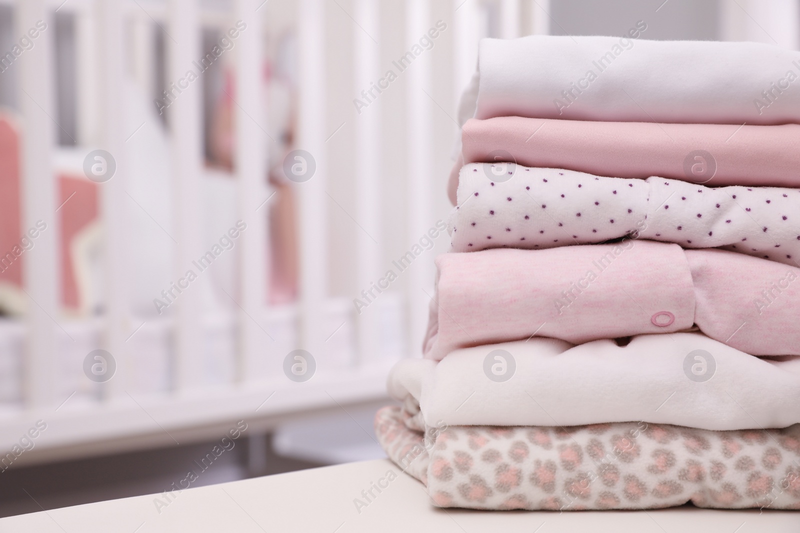 Photo of Stack of clean girl's clothes on table indoors. Space for text