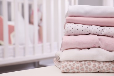 Stack of clean girl's clothes on table indoors. Space for text