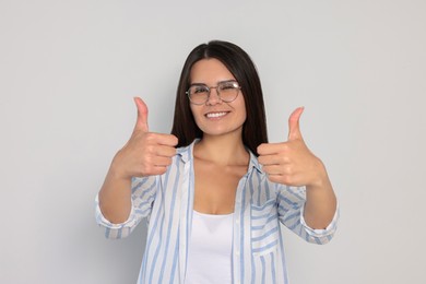 Photo of Young woman showing thumbs up on white background