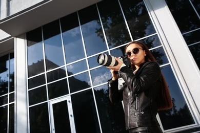 Private detective with camera spying near building on city street