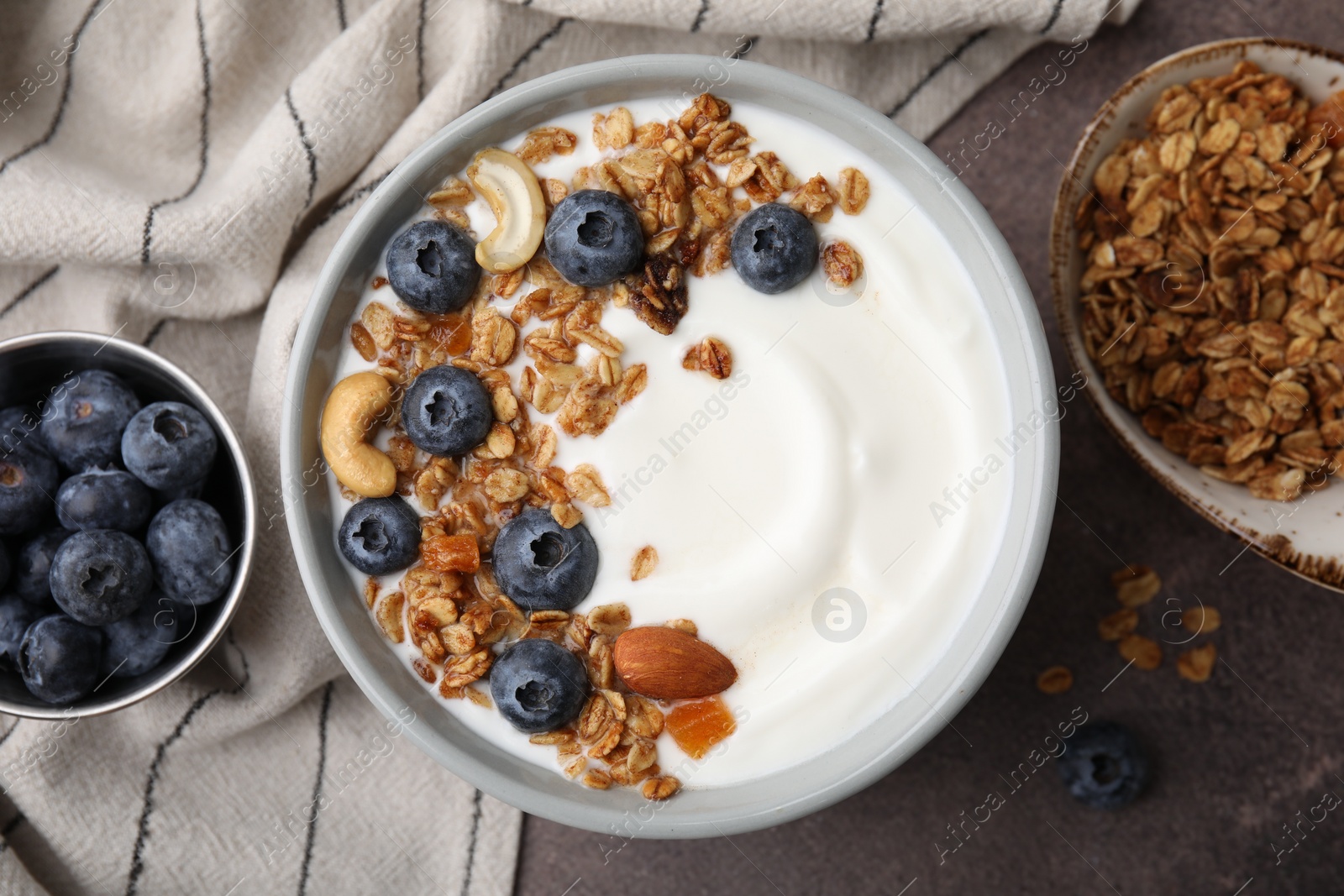 Photo of Bowl with yogurt, blueberries and granola on grey table, top view