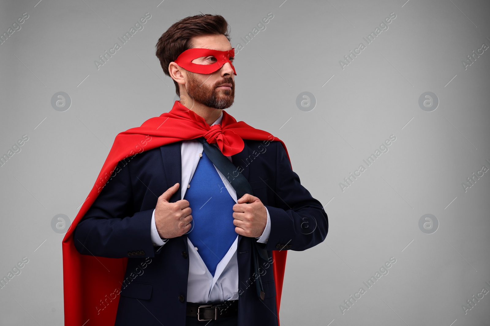 Photo of Confident businessman wearing superhero costume under suit on beige background. Space for text