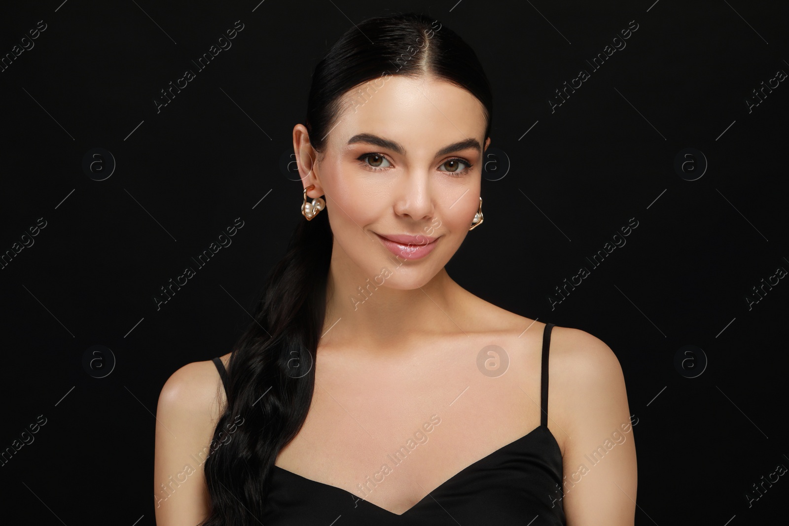 Photo of Young woman with elegant pearl earrings on black background