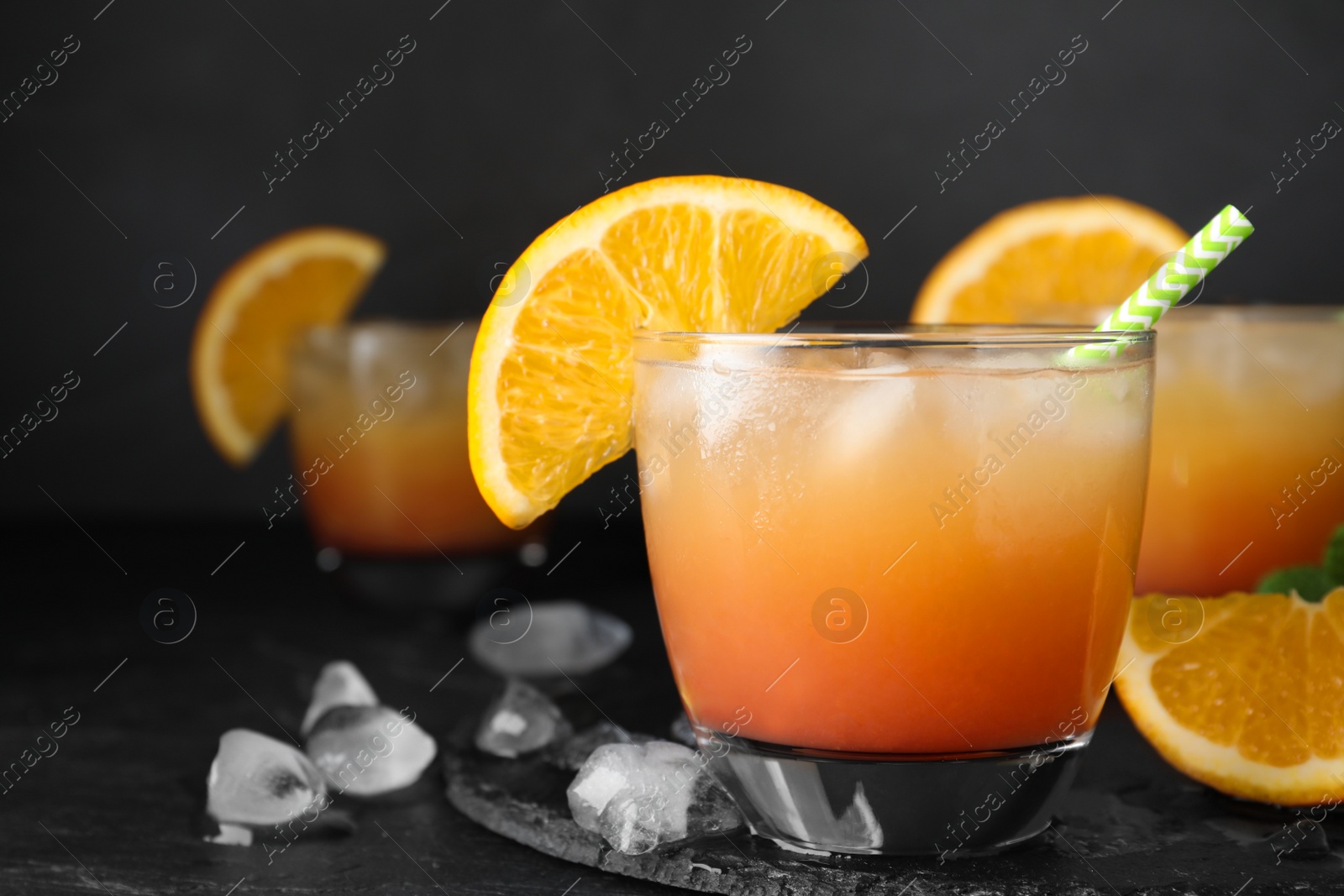 Photo of Glass of tasty tropical cocktail on black table