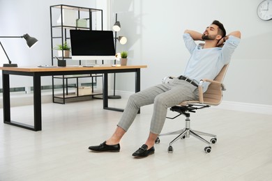 Photo of Young businessman relaxing in office chair at workplace