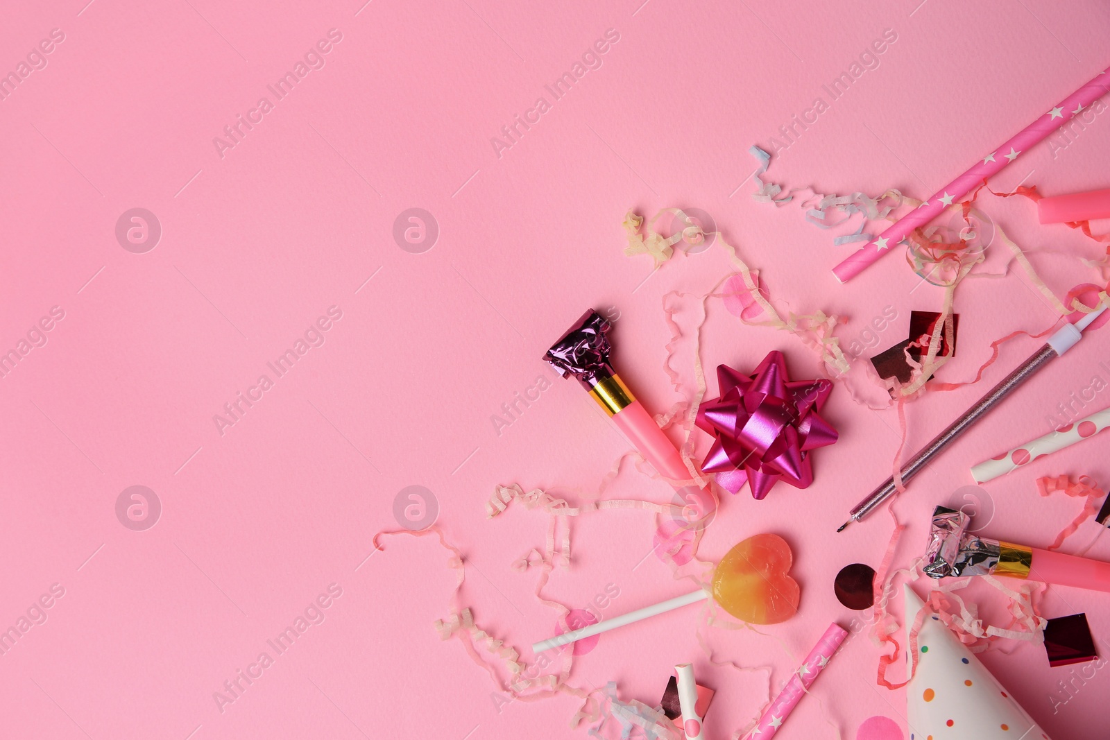 Photo of Party blowers, lollipop and festive decor on pink background, flat lay. Space for text