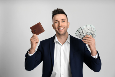 Photo of Happy man with cash money and wallet on light grey background