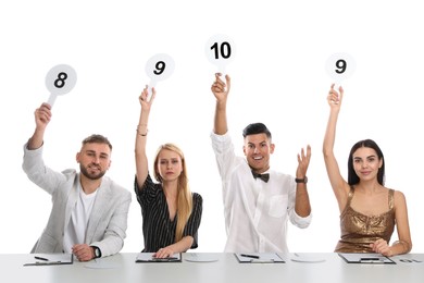 Panel of judges holding different score signs at table on white background