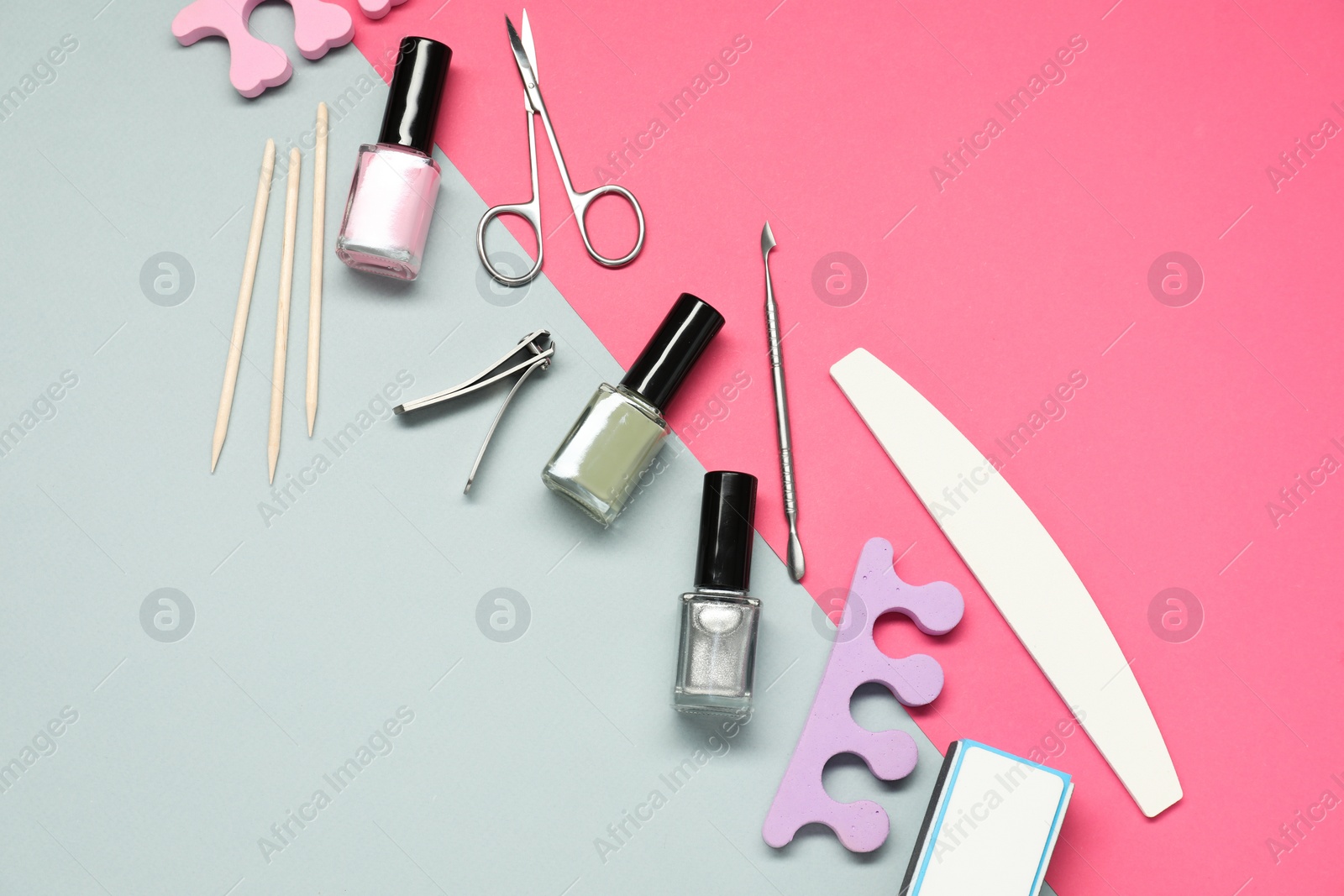 Photo of Nail polishes and set of pedicure tools on color background, flat lay