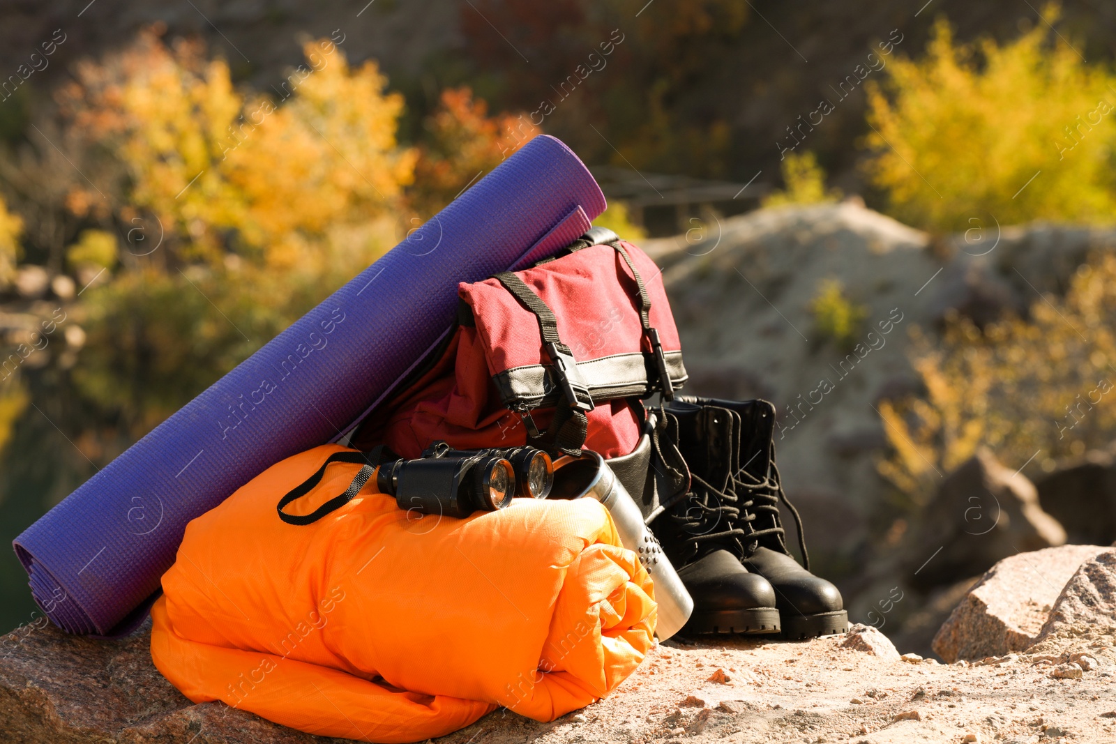 Photo of Set of camping equipment with sleeping bag on ground outdoors. Space for text