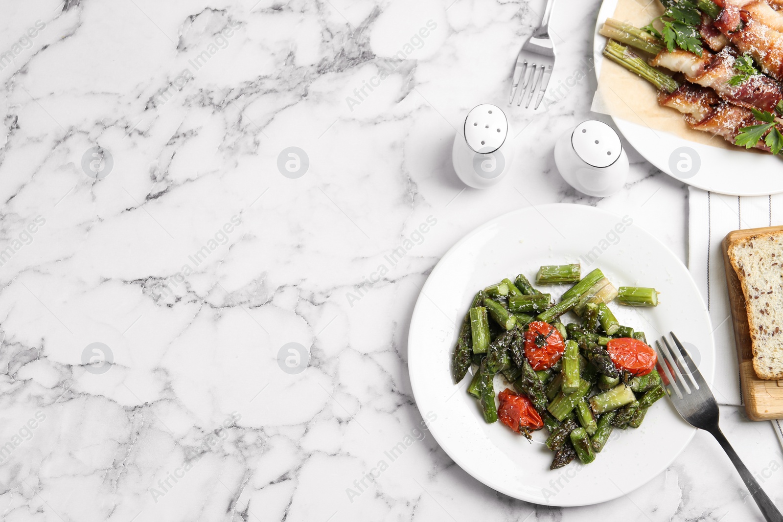 Photo of Dishes with oven baked asparagus served on white marble table, flat lay. Space for text