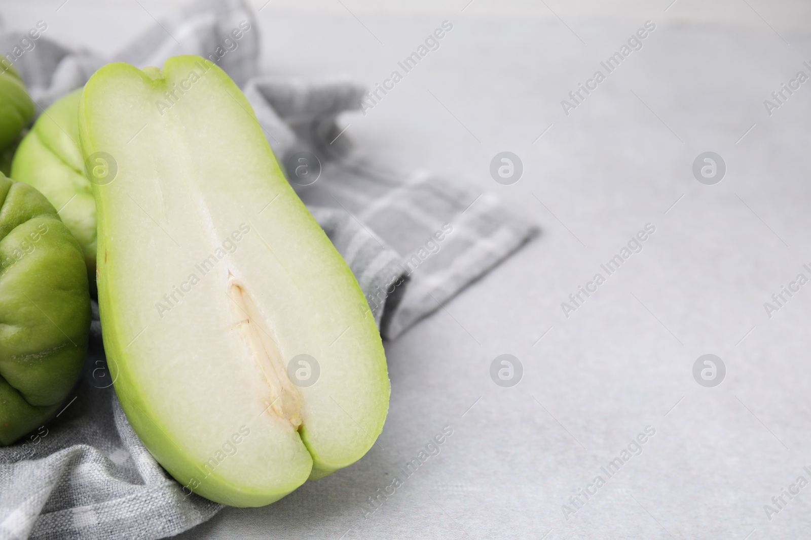 Photo of Cut and whole chayote on gray table, closeup. Space for text
