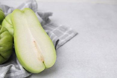Cut and whole chayote on gray table, closeup. Space for text