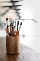 Holder with makeup brushes on table