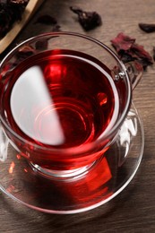 Cup of fresh hibiscus tea on wooden table, above view