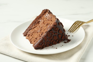Piece of delicious chocolate truffle cake and fork on table, closeup