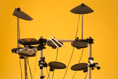 Photo of Modern electronic drum kit on yellow background. Musical instrument