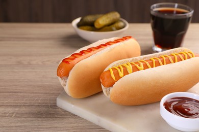 Photo of Tasty hot dogs with mustard and ketchup on wooden table. Space for text