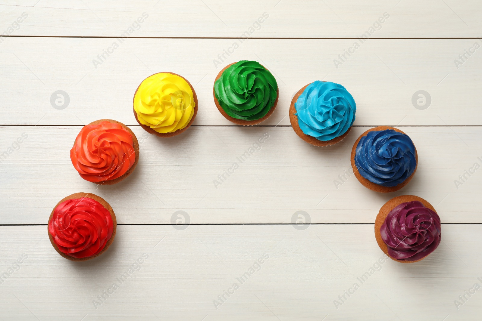 Photo of Many delicious colorful cupcakes on white wooden table, flat lay. Space for text