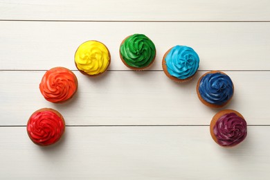 Many delicious colorful cupcakes on white wooden table, flat lay. Space for text