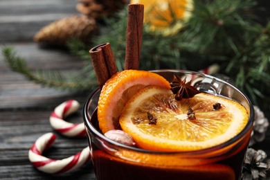 Photo of Cup of tasty mulled wine on black wooden table, closeup