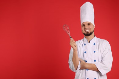 Photo of Happy professional confectioner in uniform holding whisk on red background. Space for text