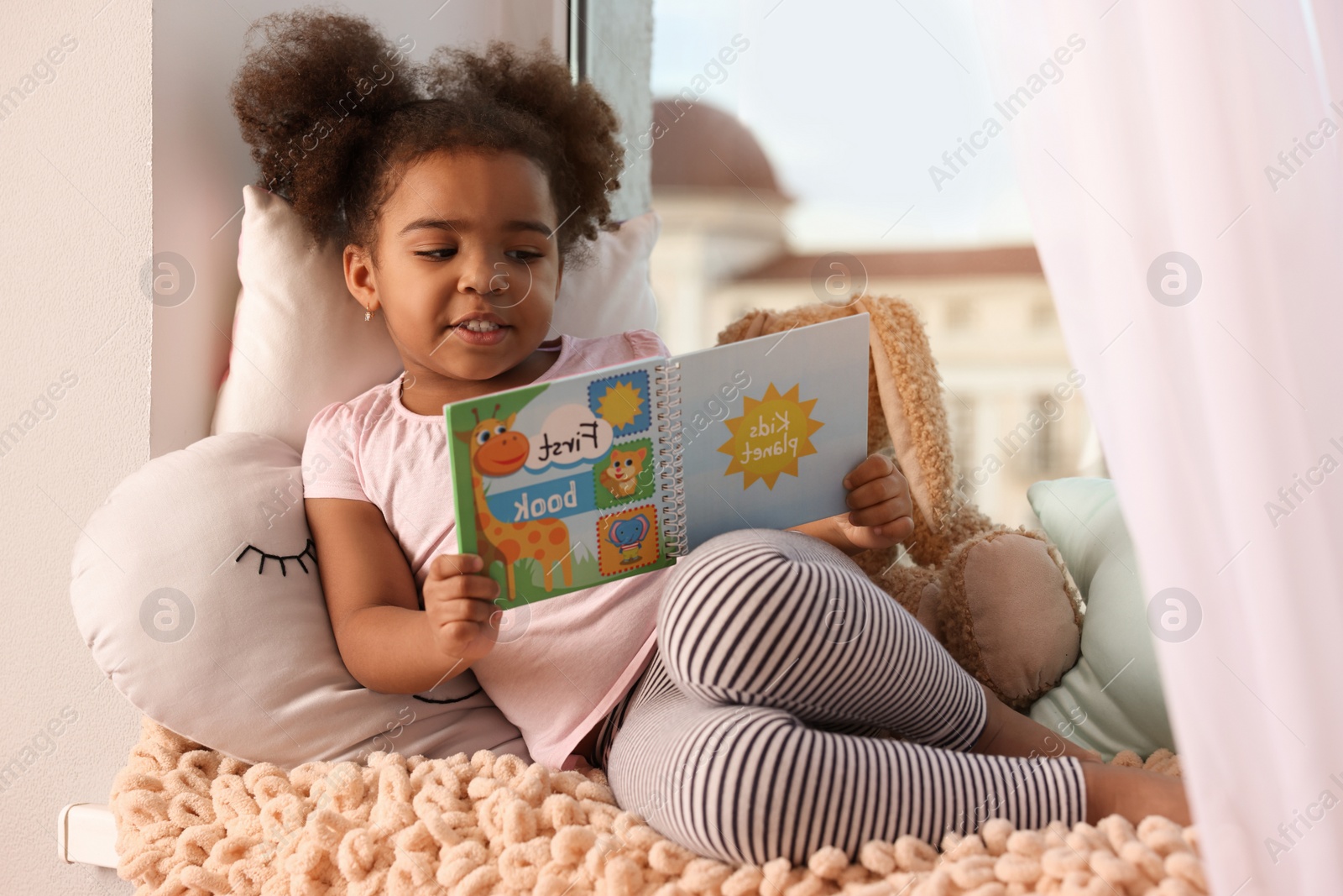 Photo of African American girl reading book at home