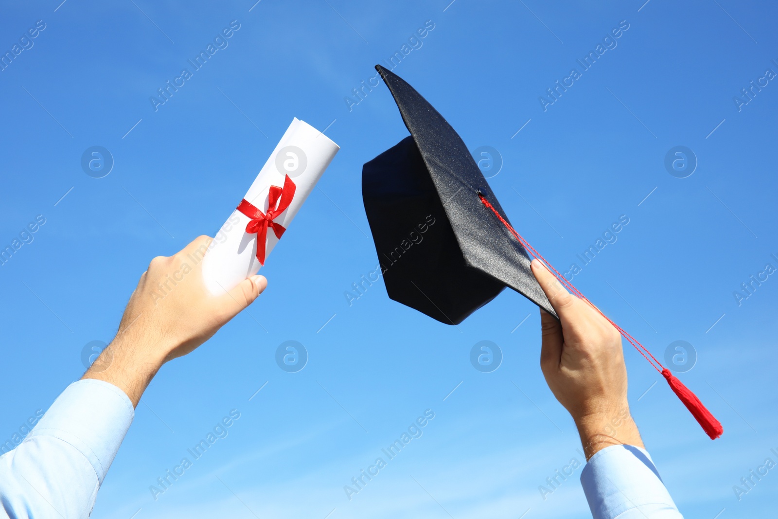 Photo of Student with graduation hat and diploma against blue sky, closeup